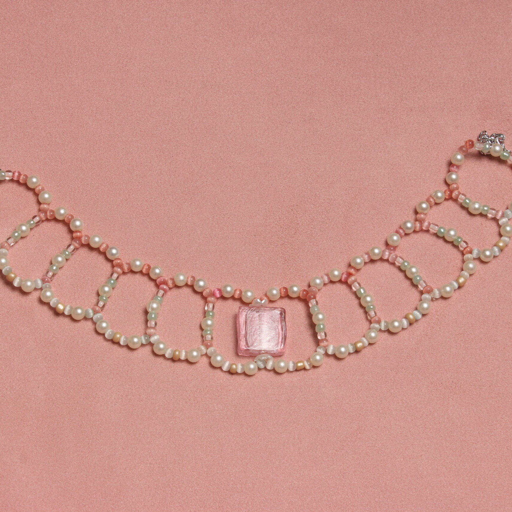 Collier vintage ras le cou. Perles fines, pastel. Alternance de couleurs. Au centre une magnifique perle en verre de Murano carrée rose pale. Taille ajustable grâce à la chaînette argentée