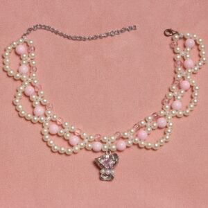 Collier en perles vintage. 2 rangées de perles blanches et rose pales et une troisième rangée formant des arcs de cercles en perles blanches. Pendentif argenté avec une pierre rose pâle et 3 petites perles blanches nacrées au centre du collier. Taille ajustable grâce à la chaînette argentée.