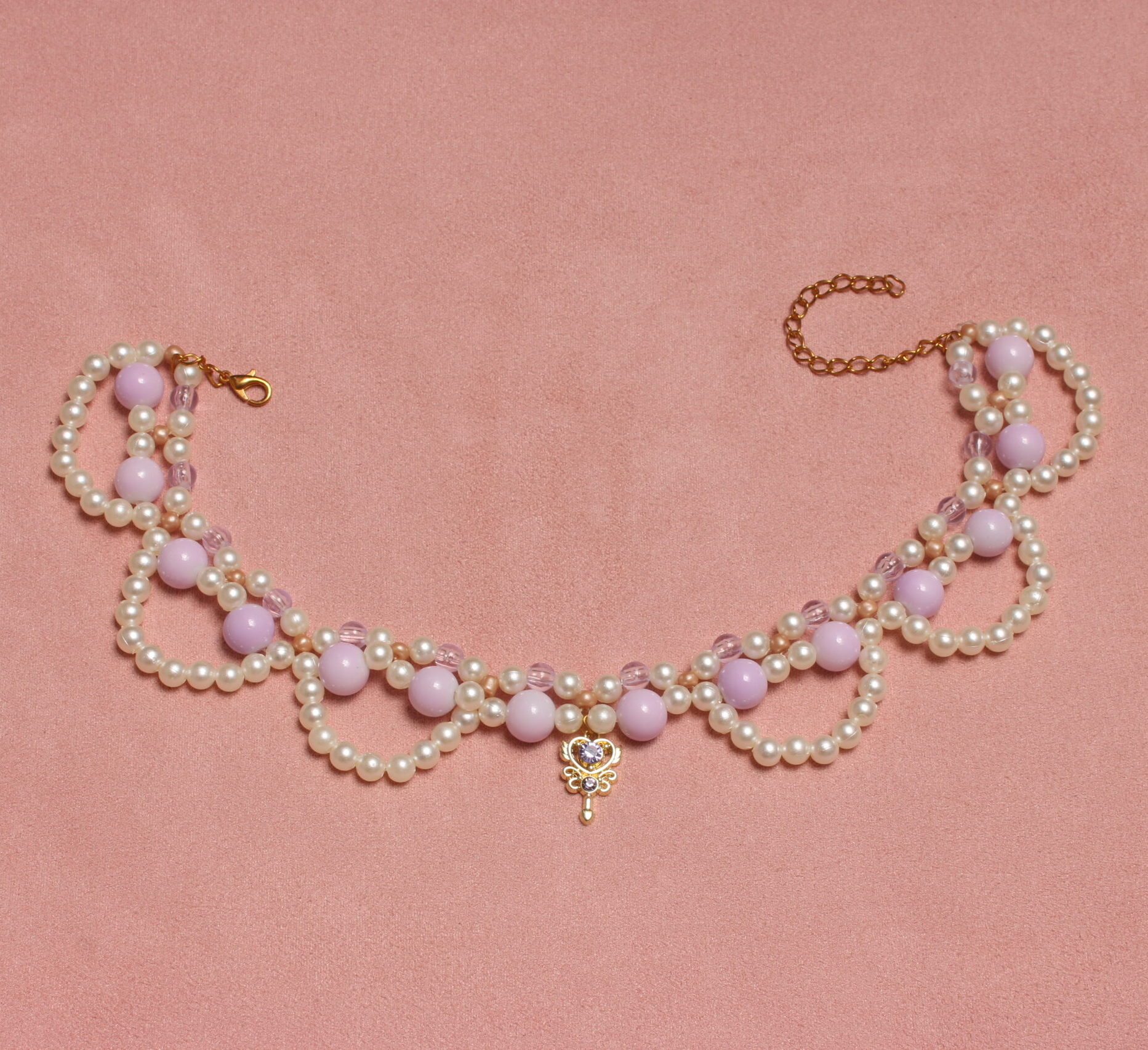 Collier en perles vintage. 2 rangées de perles blanches et parme, composées de petites perles pour la rangée la plus près du cou et de perles parme plus grosses pour la seconde rangée. Arcs de cercles en perles blanches nacrées pour donner du relief au collier. Pendentif doré en forme de clé avec une pierre étincelante parme au centre.