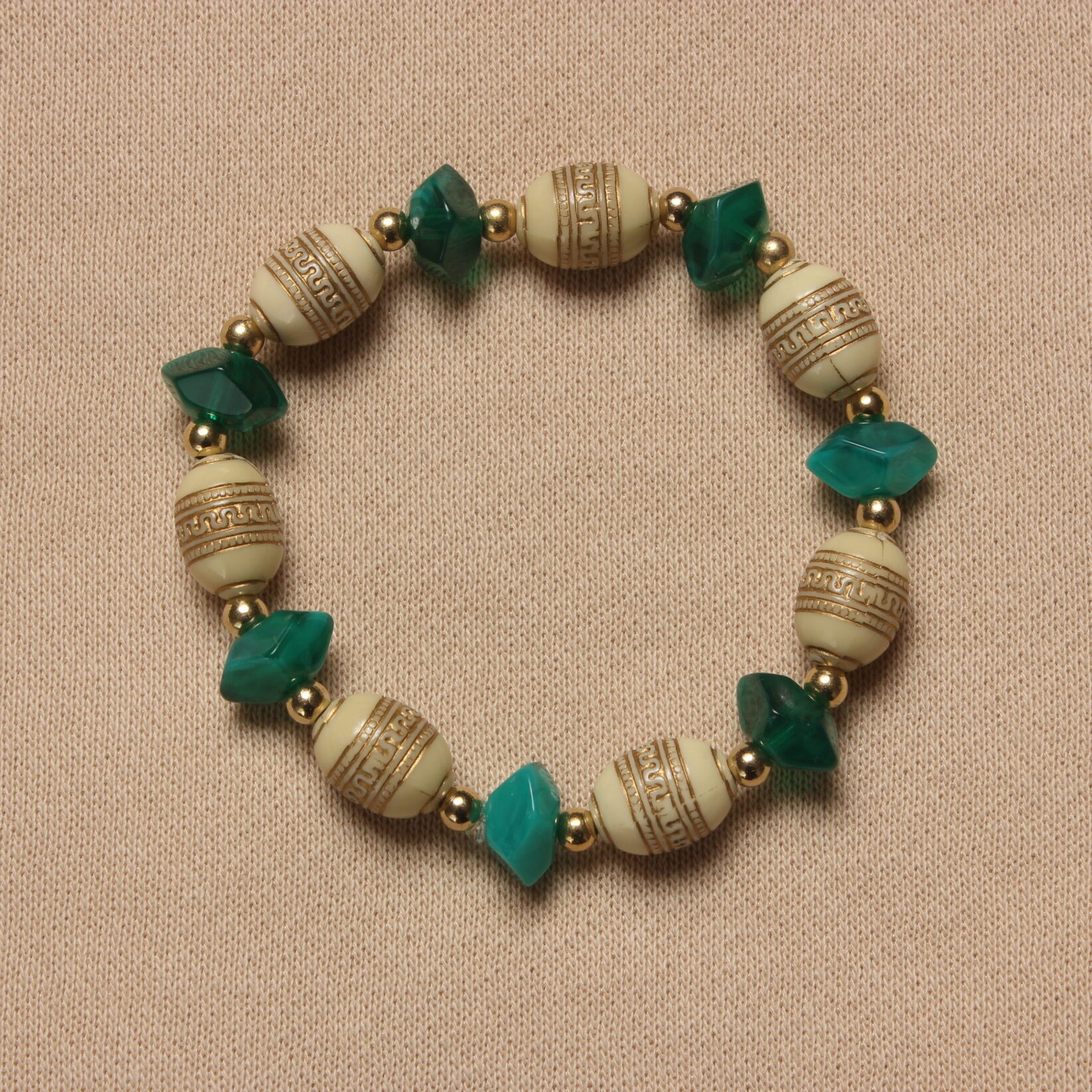 Bracelet vintage alternant des perles beiges avec des motifs dorés de forme allongée et des perles plus triangulaires bleu canard. Petites perles dorées entre chaque perle