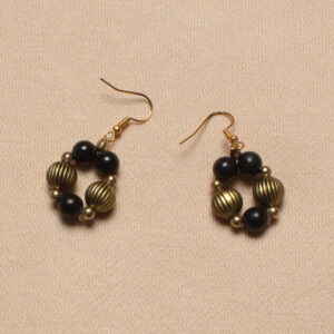 Boucles d'oreilles pendantes. Attache dorée. La boucle d'oreille forme un cercle composé d'une alternance de perles dorées à rainures et noires.