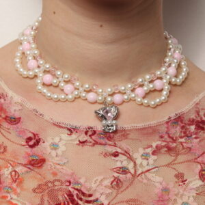 Collier en perles vintage. 2 rangées de perles blanches et rose pales et une troisième rangée formant des arcs de cercles en perles blanches. Pendentif argenté avec une pierre rose pâle et 3 petites perles blanches nacrées au centre du collier. Taille ajustable grâce à la chaînette argentée.