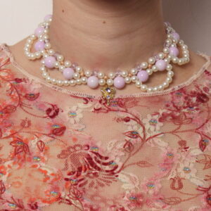 Collier en perles vintage. 2 rangées de perles blanches et parme, composées de petites perles pour la rangée la plus près du cou et de perles parme plus grosses pour la seconde rangée. Arcs de cercles en perles blanches nacrées pour donner du relief au collier. Pendentif doré en forme de clé avec une pierre étincelante parme au centre.