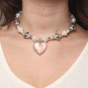 Collier en perles vintage. Alternance de perles blanches nacrées et grises. Pendentif en forme de cœur transparent au centre. Formes et grosseurs variées. Taille ajustable grâce à la chaînette argentée