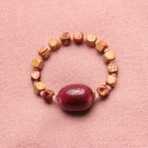 Bracelet vintage: alternance de perles en bois carrées et de petites perles de verre rondes rose pâles. Grosse perle ovale grenat au centre