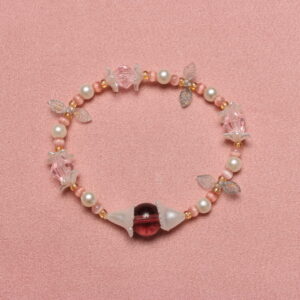 Collier de perles dans les tons pastel. Il est composé de perles rondes blanches nacrées et roses pâles. De petits pétales verts clairs et des fleurs blanches nacrées apportent une touche printanière. Il est rehaussé d'une très belle perle upcyclée violette bordeaux en verre délicatement enveloppée de 2 fleurs blanches nacrées.