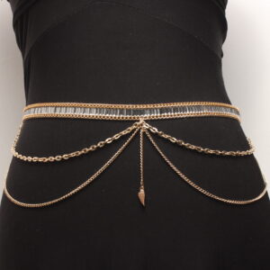 Tour de ventre composé d'une fine ceinture en strass gris enveloppés de 2 chaînettes dorées qui sont plaquées à la ceinture . 2 autres chaînettes dorées (une petite et une plus grande) tombant sur les hanches sont situées de chaque côté. Au centre, il y a une petite chaînette dorée verticale terminée par une petite aile dorée. Chaînette d'extension dorée à l'arrière