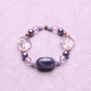 Bracelet élastique vintage. Il est composé d'une déclinaison de perles parme et cuivrées, 2 perles en forme de losange parme transparentes et une magnifique perle ovale violette entourée de 2 intercalaires dorés.