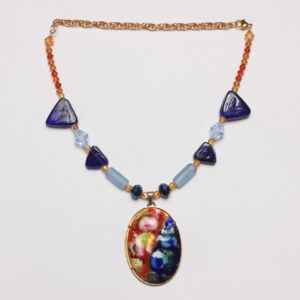 Collier en perles bleues et oranges. Perles triangulaires grosses et petites bleues marines en verre, perles bleues claires en forme de tube en verre. Petites perles géométriques orange en acrylique. Au centre un magnifique pendentif en émail d'un côté orange avec des fleurs jaunes et de l'autre bleu foncé avec des fleurs bleues claires. Chaînette d'extension dorée.