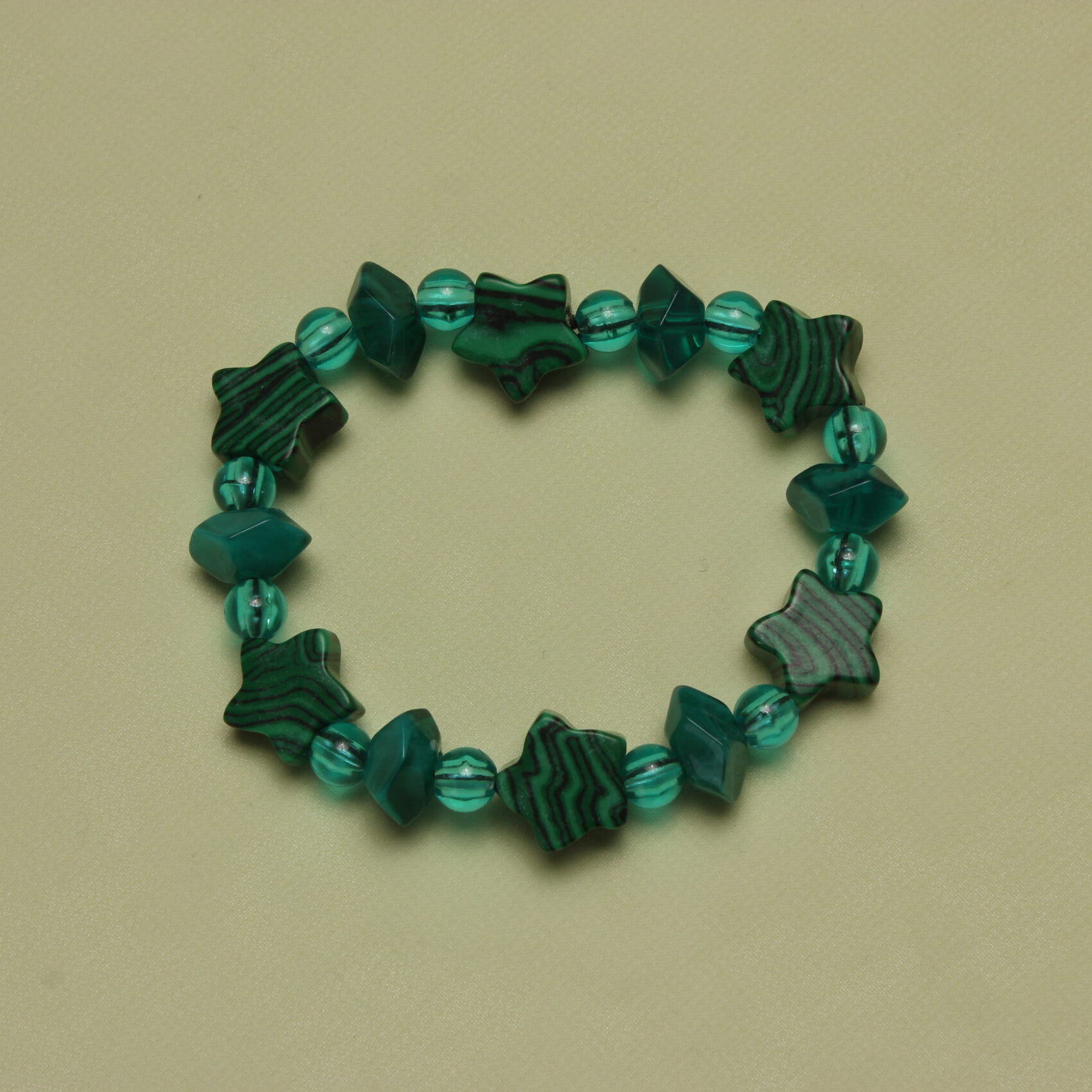 Bracelet vert sapin composé d'une alternance de perles rondes transparentes, de perles géométriques et de perles en forme d'étoile.