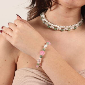 Ensemble collier et bracelet. Le collier est un ras de cou composé de 2 rangées de perles de verre. La plus proche du cou est créée avec des perles blanches et la seconde avec une alternance de perles blanches et vertes. Chaînette d'extension à l'arrière. Le bracelet se compose des mêmes perles vertes que le collier auxquelles s'ajoutent de petites perles roses pâles, des perles roses en forme de fleur et des perles de céramique blanches où sont peintes des fleurs. Fermoir argenté