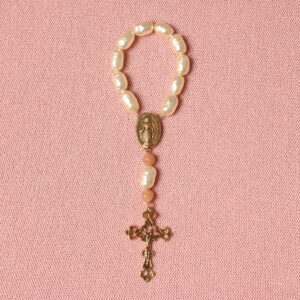 Dizainier composé de perles ovales beiges et de 2 perles roses pâles. Connecteur central et croix en alliage de couleur dorée. Représentation de la vierge Marie sur le connecteur et de Jésus Christ sur la croix