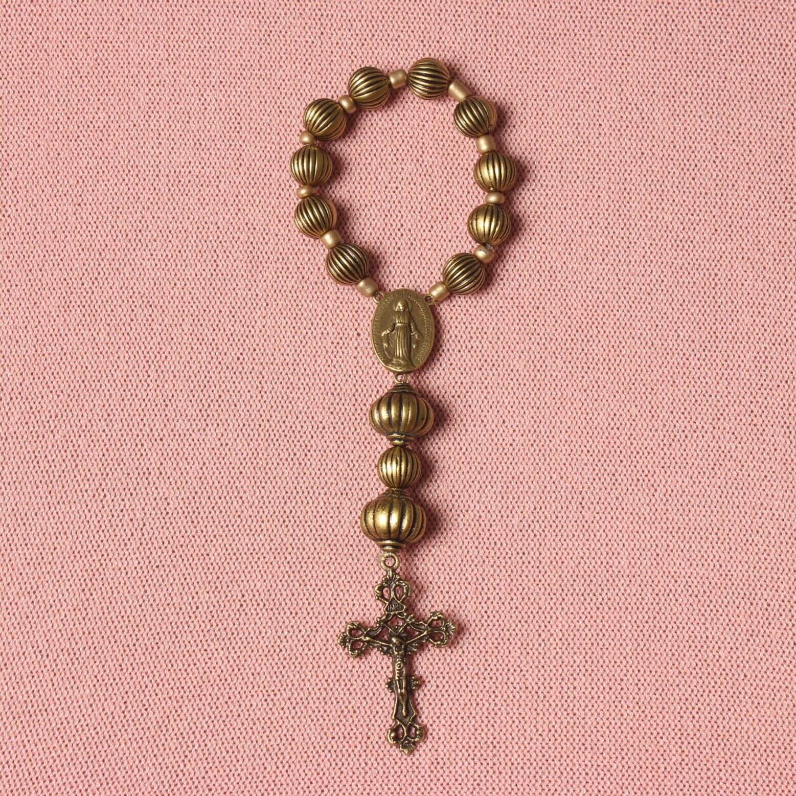 Dizainier composé de perles rondes noires striées de dorées et de 2 perles ovales au même motif. Connecteur central et croix en alliage de couleur bronze. Représentation de la vierge Marie sur le connecteur et de Jésus Christ sur la croix