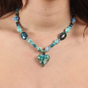 Collier en perles bleues turquoises rondes et ovales de grosseurs variées. Au centre se trouve un magnifique pendentif bleu turquoise en forme de cœur. Chaînette d'extension argentée à l'arrière.