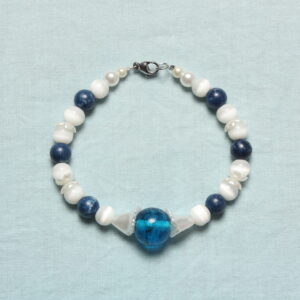 Bracelet composé de perles en pierre blanches et bleues marines upcyclées. De petites fleurs blanches nacrées apportent une délicate touche printanière. Il est rehaussé d’une magnifique perle upcyclée bleue roi en verre au centre enveloppé de 2 fleurs blanches nacrées.