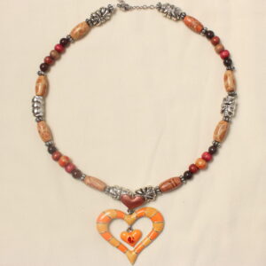 Ce collier est constitué d'un gros pendentif en forme de cœur rayé orange et rouge. au dessus de ce cœur est disposé un deuxième plus petit et orange également. A l’intérieur du gros cœur se trouve encore un petit orange avec une strass rouge au centre. Ce collier est symétrique autour du gros pendentif. il y a d'abord une perle argentée ovale avec des petits détails, suivie d'une perle allongée en bois avec des petits détails marrons et rouges entourées d'intercalaires argentées. ensuite il y a une suite de perles disposées symétriquement autour d'une perle en bois orange. Une petite perle en pierre marron, et une autre en bois rouge. Ensuite. il y a deux perles longues en bois entourées de petites intercalaires qui sont autour d'une perle longue argentée. l'alternance de perles en bois et en pierre recommence avant de finir par une longue perle en bois entourée d'intercalaires et suivie d'une dernière perle argentée. Le collier se finit avec une petite chaînette d’extension ainsi qu'un fermoir pour fermer le collier.