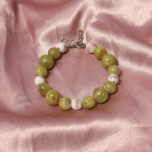 Ce bracelet est constitué de 5 perles en céramique blanches et roses avec des petits détails fleuri. entre elles se trouve des perles vertes de différentes tailles.