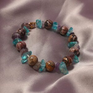 Ce bracelet est constitué d’une alternance de perles en verre aplaties bleues et violettes, ainsi que de perles probablement en pierre. Il se ferme à l’aide d’un fermoir doré.