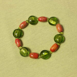 Ce bracelet est constitué d’une alternance de perles en bois ovales rouge et orange, ornées de petits détails uniques, et de perles rondes et aplaties en verre vert. Chaque perle est séparée par de petites perles vertes en verre, créant ainsi une harmonie de couleurs et de matières tout au long du bracelet.