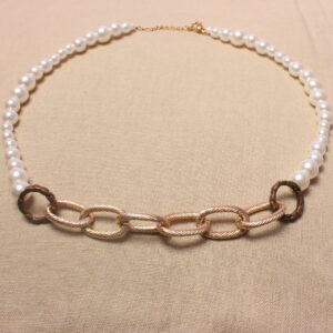 Ce collier maximaliste possède une grosse chaîne dorée en son centre. À l’extérieur de celle-ci se trouve une alternance de perles en verre ciré et de perles nacrées blanches. Les deux chaînettes sont séparées par un anneau doré foncé. Le collier se ferme grâce à un fermoir doré situé à son extrémité.