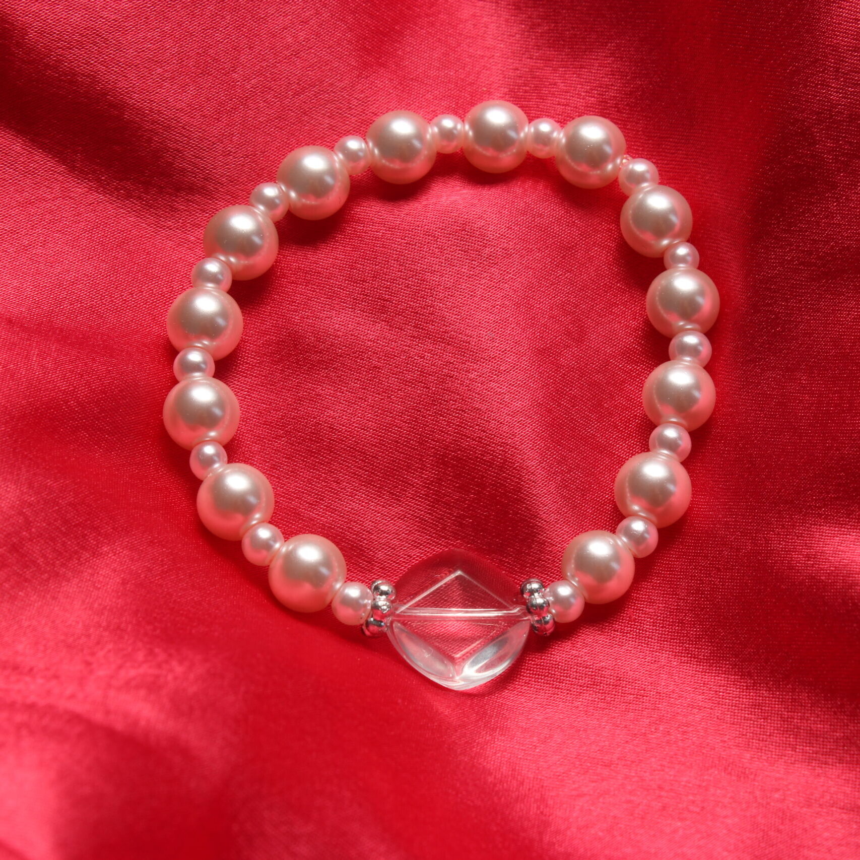 Ce bracelet est composé de perles en verre roses pâles et au centre d'une magnifique perle transparente en verre en forme de losange entourée de 2 intercalaires argentés.