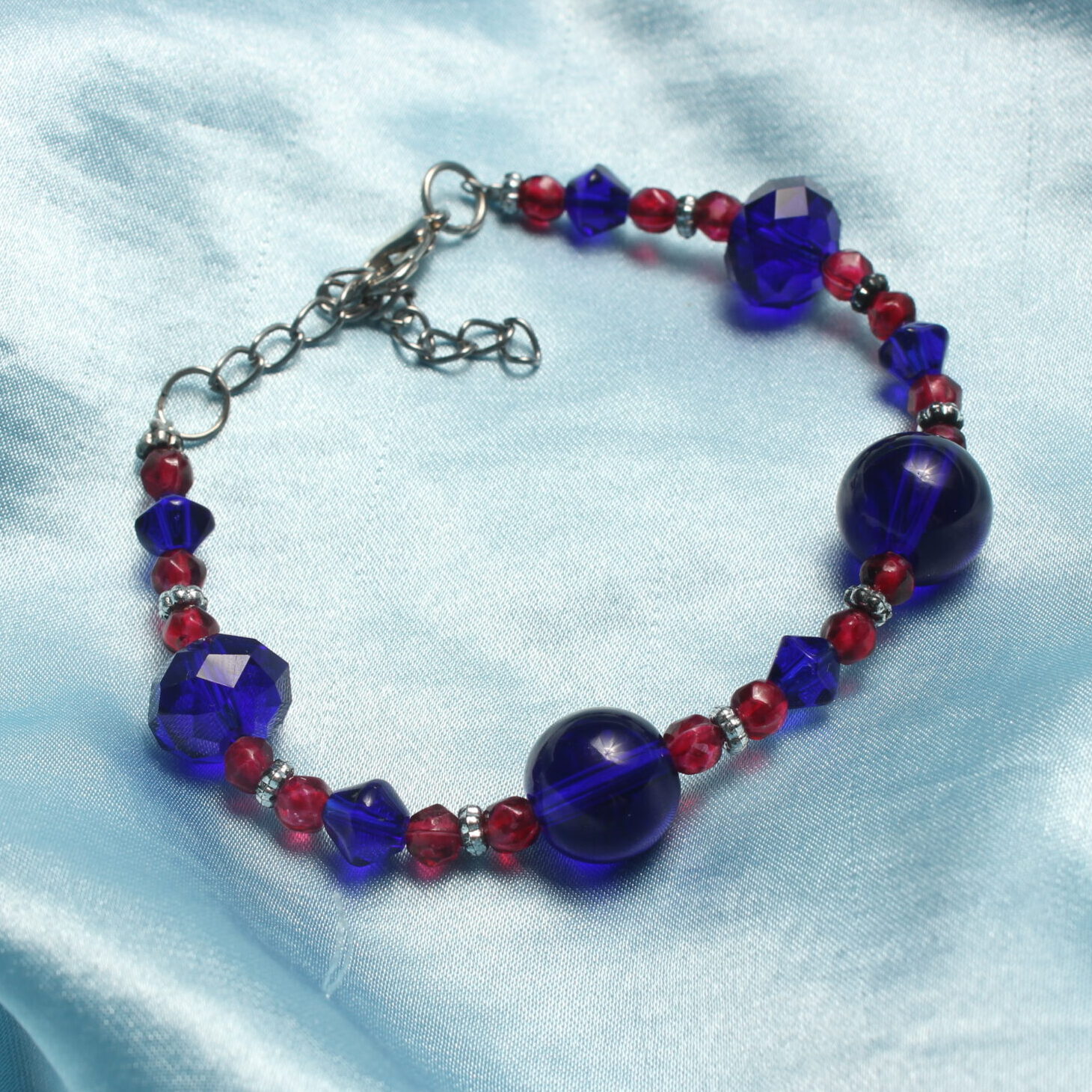 Ce bracelet est constitué de perles en verre à facette bleues, des perles rondes en verre bleues nuit et des petites perles à facette roses. Il y a également des petites intercalaires argentées. Le bracelet se ferme grâce à un fermoir et une chaînette.