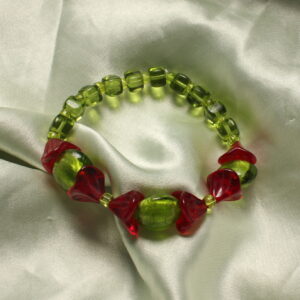 Ce bracelet est constitué de trois grosses perles vertes situées à l’avant du bracelet. Elles sont toutes recouvertes de perles rouges en forme de fleurs. Le bracelet se poursuit ensuite avec de petites perles vertes carrées. Chaque perle est séparée par de toutes petites perles vertes, créant ainsi un joli rythme tout au long du bracelet. Toutes les perles de ce bracelet sont en verre.