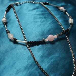 Ce collier à double rangs est constitué d'un premier en perle rose, noir et transparentes. une chaînette tombe légèrement sous celle ci. Les couleur et le style est neutre pour être portable plus facilement et pour convenir aussi bien pour les hommes que pour les femmes.
